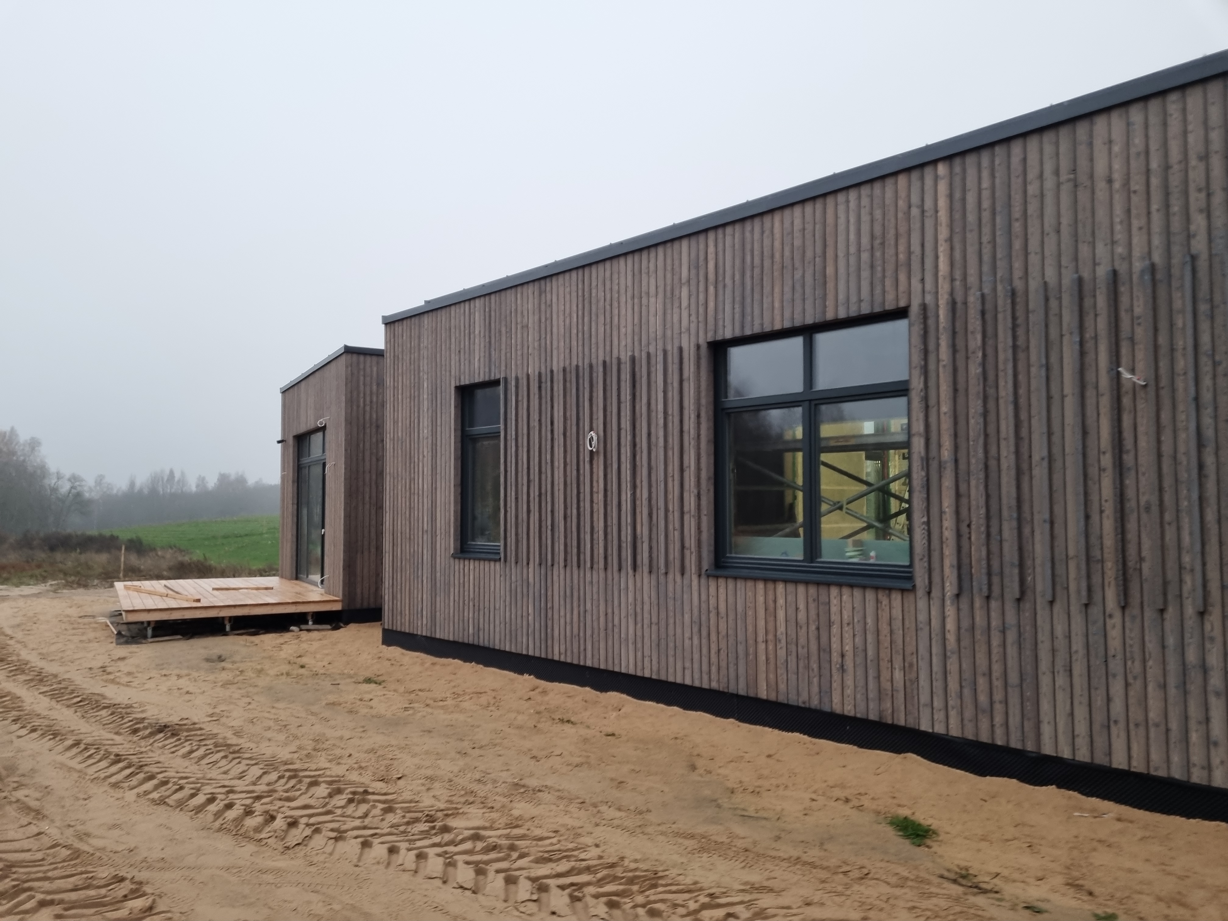 The photo shows a newly constructed wooden house under construction in the works. The exterior parts of the house are cove...